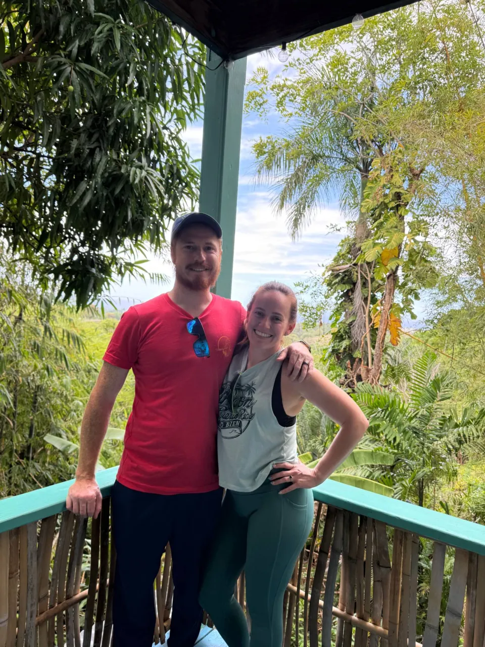 Megan and her husband smiling on a jungle-view balcony