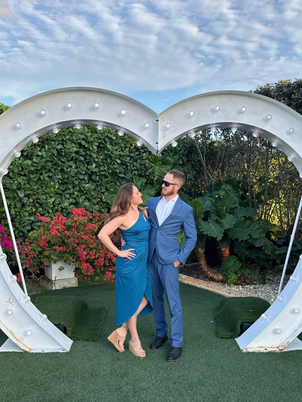 Megan and her husband dressed up under a lighted heart-shaped arch